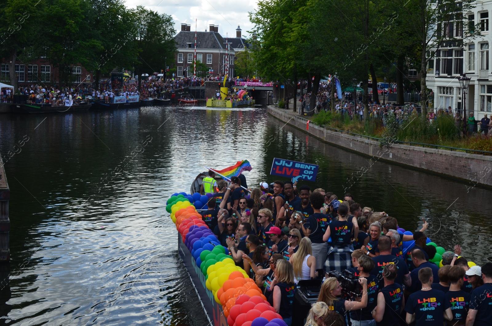 Photo of AMSTERDAM, NETHERLANDS - AUGUST 06, 2022: Many people in boats at LGBT pride parade on river