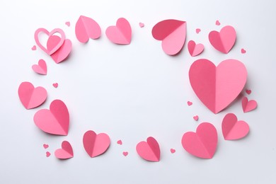 Photo of Frame of pink paper hearts on white background, flat lay. Space for text