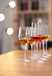 Photo of Different sorts of wine in glasses prepared for tasting on wooden table indoors