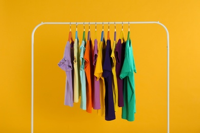Photo of Rack with stylish children clothes on yellow background