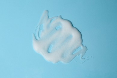 Photo of Foam on light blue background, top view. Face cleanser, skin care cosmetic