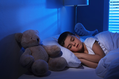 Photo of Little boy sleeping with teddy bear at home. Bedtime