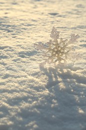 Photo of Beautiful decorative snowflake in white snow, outdoors