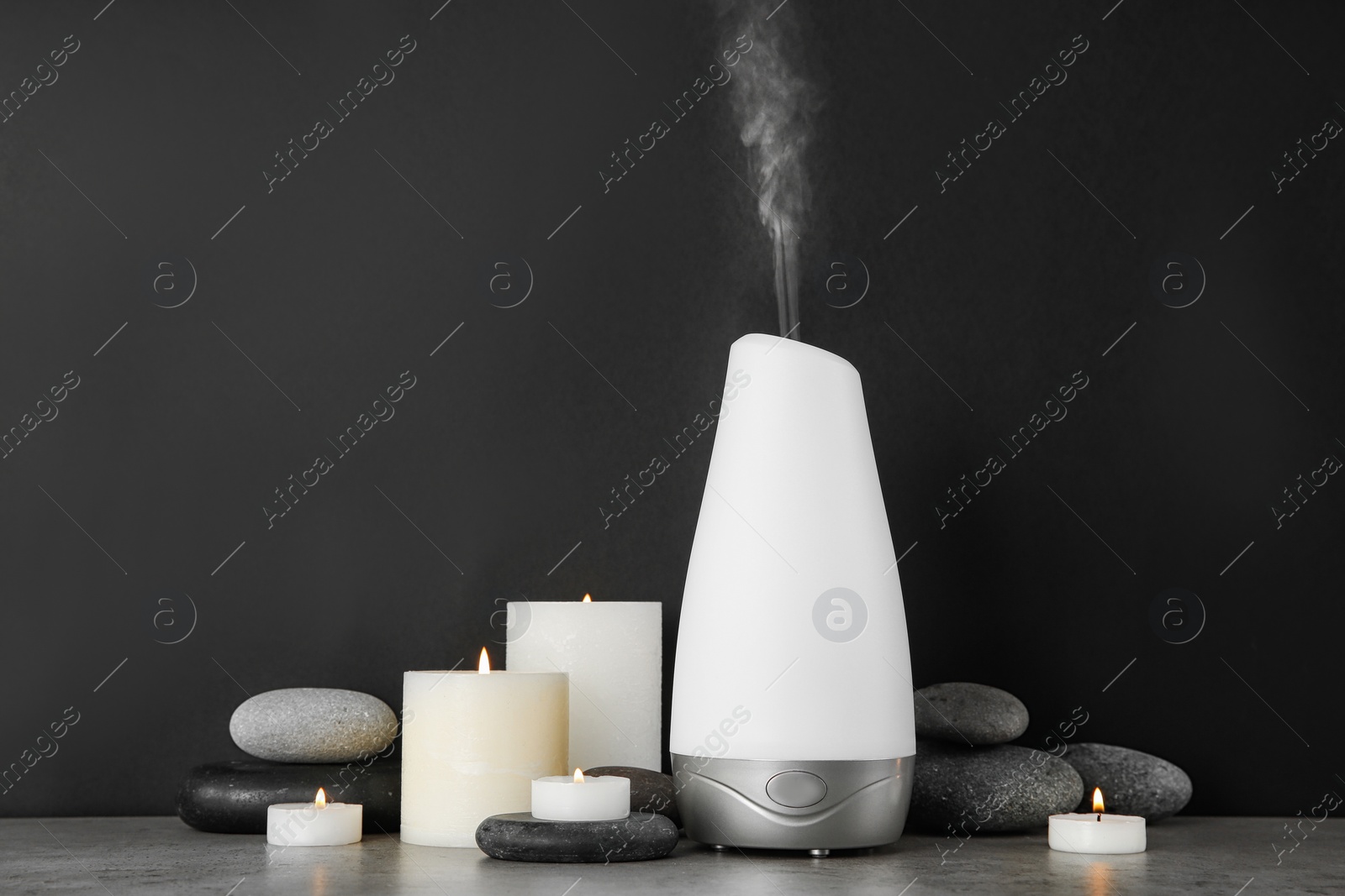 Photo of Composition with aroma humidifier on table against black background. Space for text