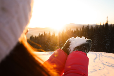 Woman holding pile of snow outdoors, closeup. Winter vacation