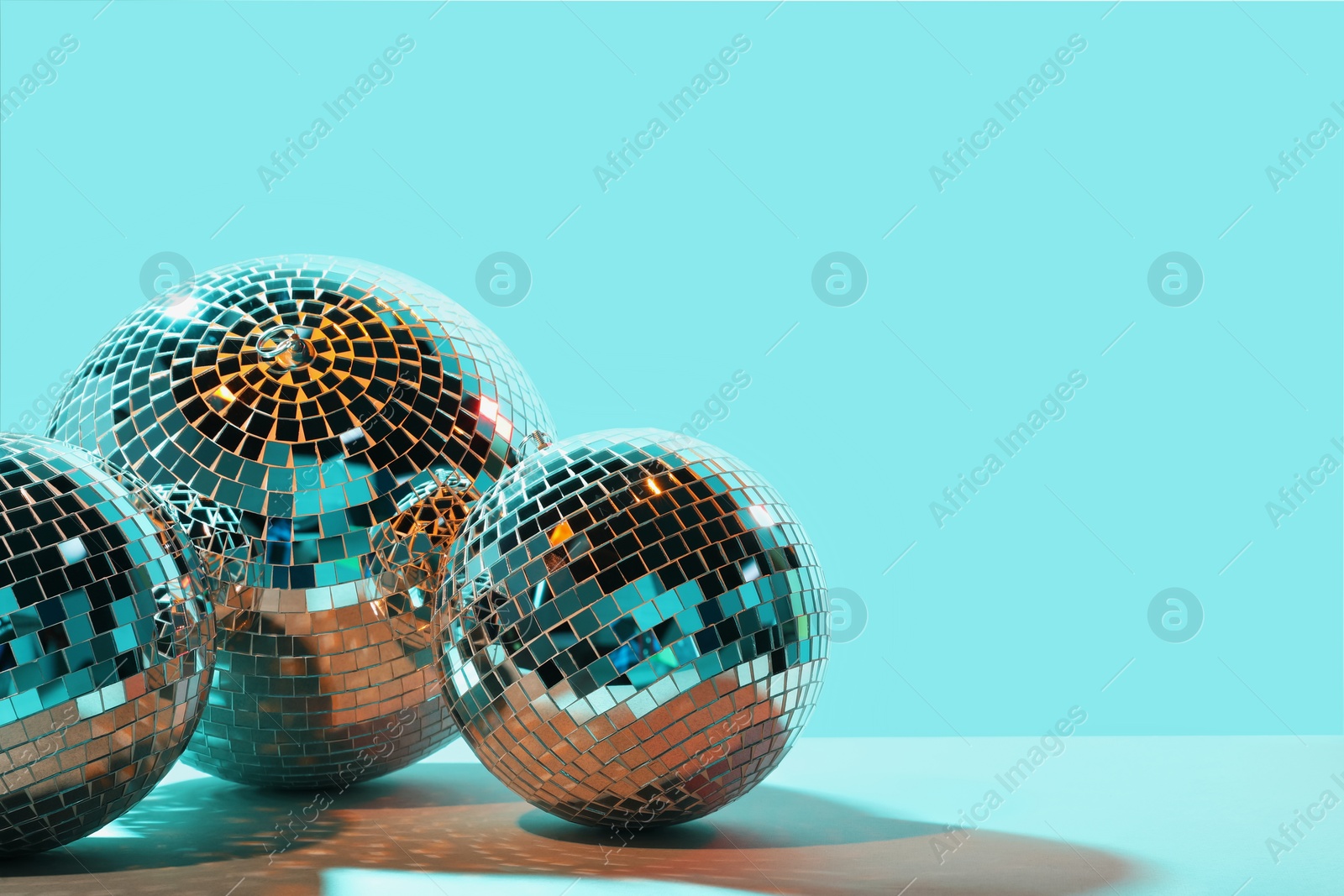 Photo of Shiny disco balls on turquoise background. Space for text