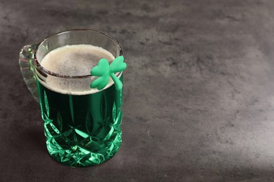 Photo of St. Patrick's day celebration. Green beer with decorative clover leaf on grey table. Space for text