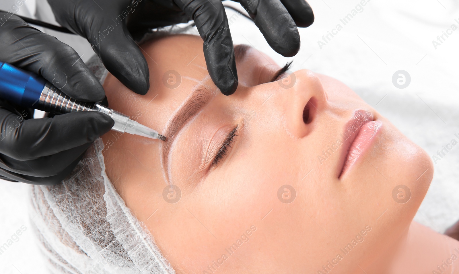 Photo of Young woman undergoing eyebrow correction procedure in salon