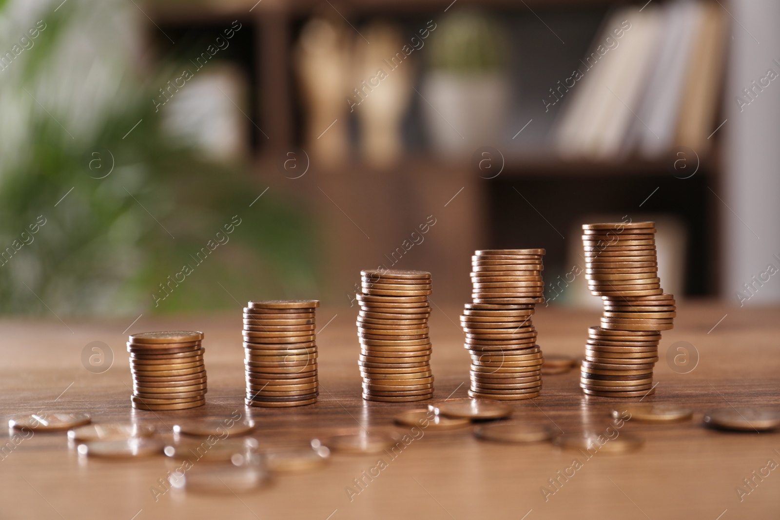 Photo of Stacks of coins on wooden table against blurred background