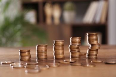 Stacks of coins on wooden table against blurred background