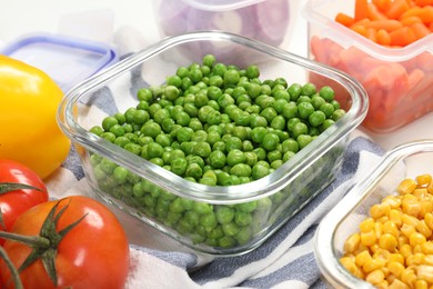 Photo of Containers with green peas and fresh products on table, closeup. Food storage