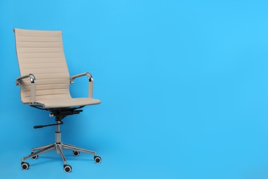 Photo of Comfortable office chair on light blue background, space for text