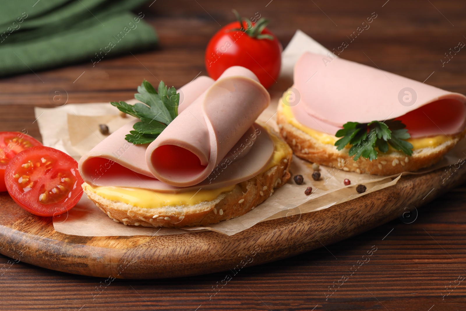 Photo of Delicious sandwiches with boiled sausage, cheese and tomatoes on wooden table, closeup