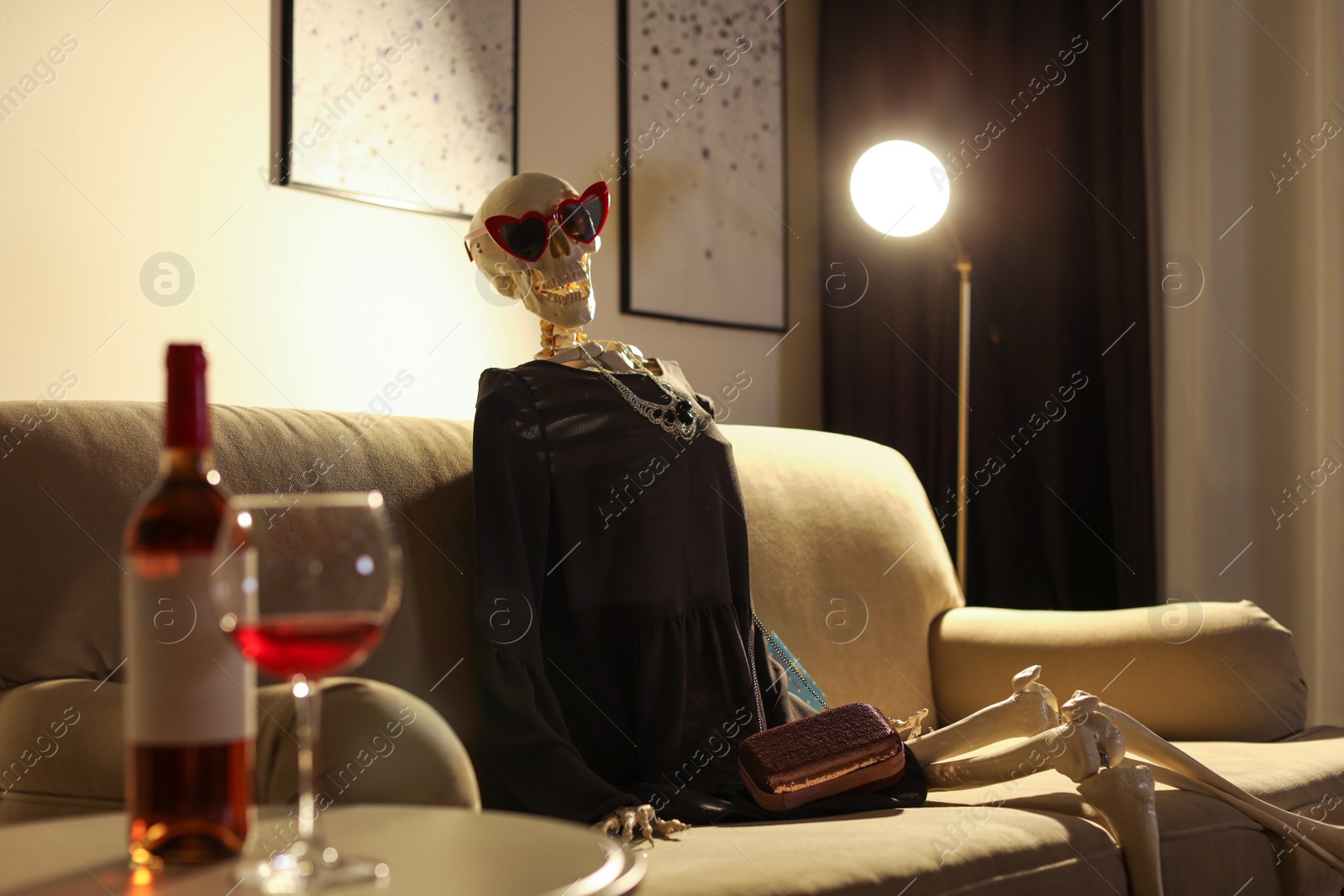 Photo of Skeleton in dress sitting on sofa at home