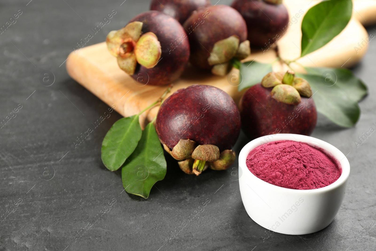 Photo of Purple mangosteen powder and fruits on black table