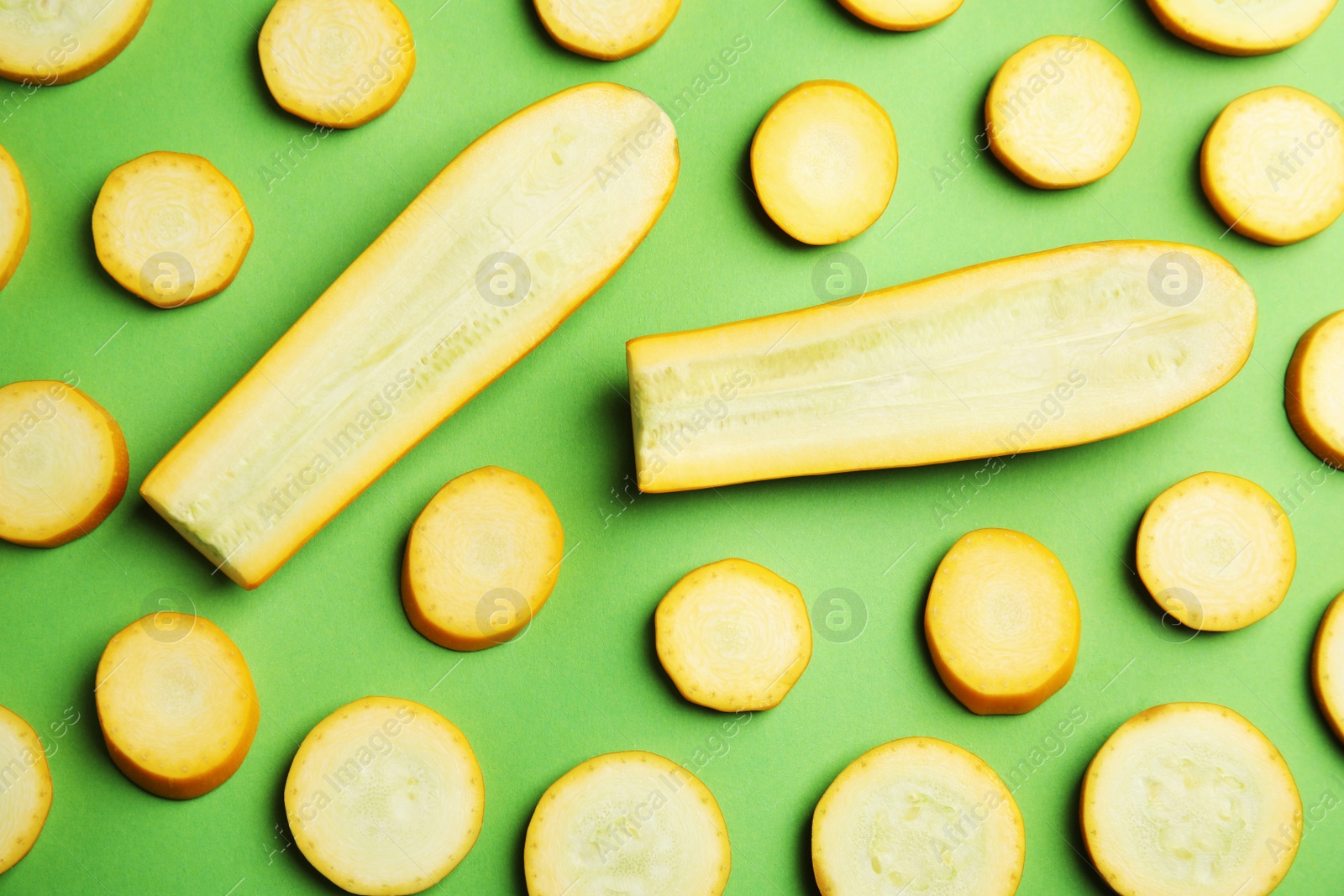 Photo of Fresh ripe cut zucchinis on green background, flat lay