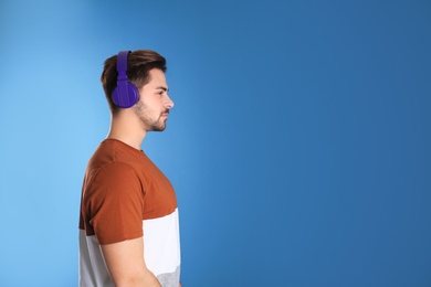 Handsome man with headphones on color background. Space for text