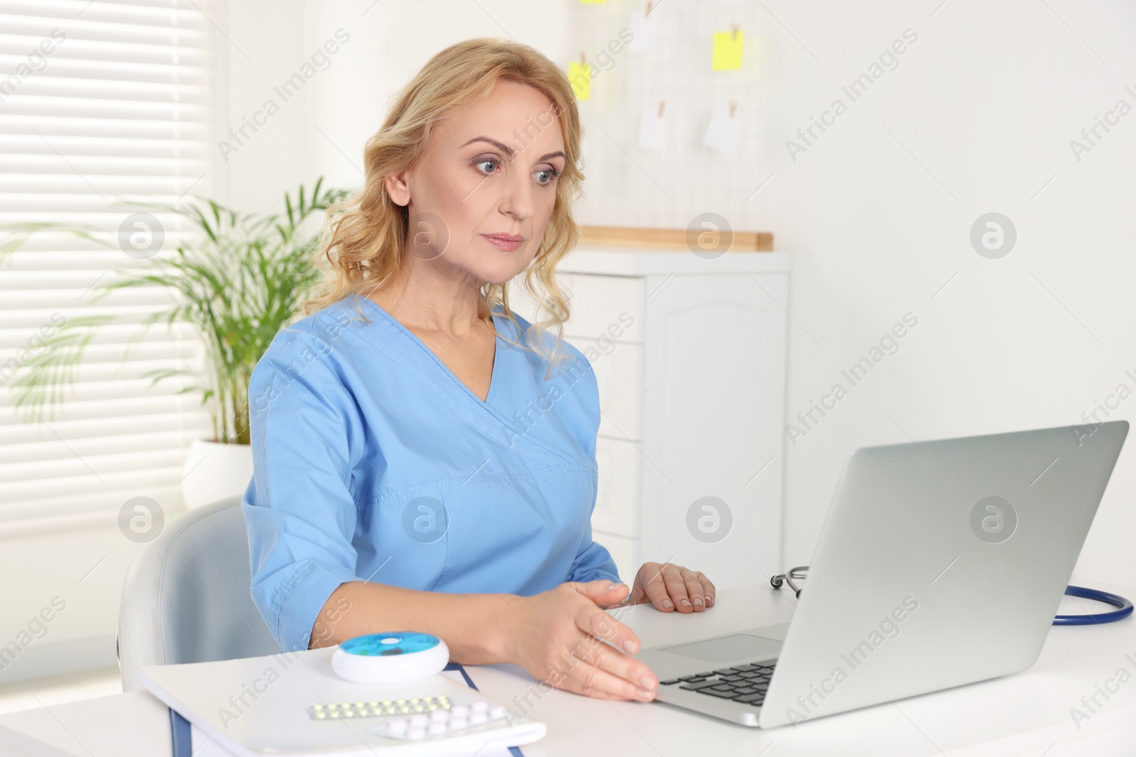 Photo of Doctor with laptop consulting patient in clinic. Online medicine concept