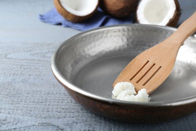 Photo of Frying pan with organic coconut cooking oil and spatula on grey wooden table, closeup