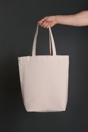 Photo of Man holding cotton shopping eco bag on grey background. Mockup for design