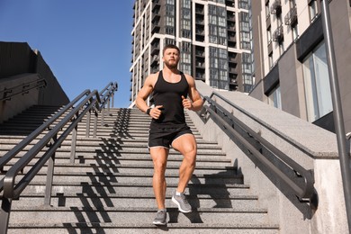 Man running down stairs outdoors on sunny day, low angle view