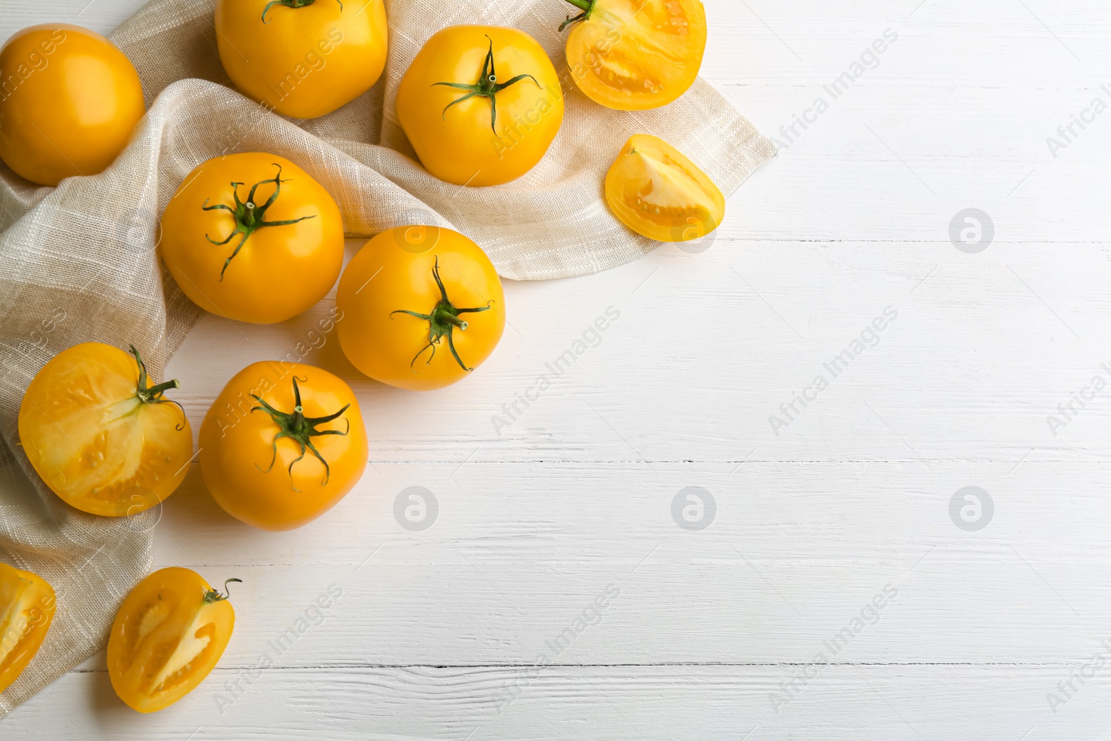 Photo of Ripe yellow tomatoes on white wooden table, flat lay. Space for text