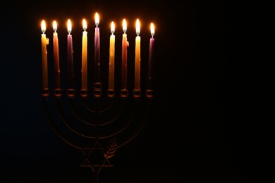 Photo of Hanukkah celebration. Menorah with burning candles in darkness, space for text