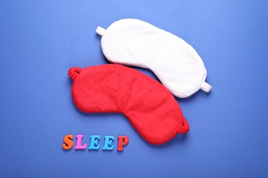 Photo of Soft sleep masks and word Sleep made of colorful letters on blue background, flat lay