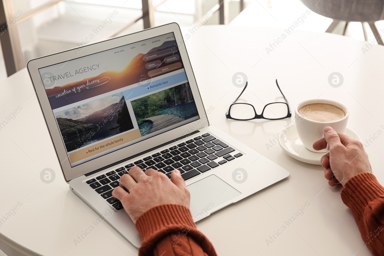 Photo of Man booking tickets online on laptop at white table, closeup. Travel agency concept