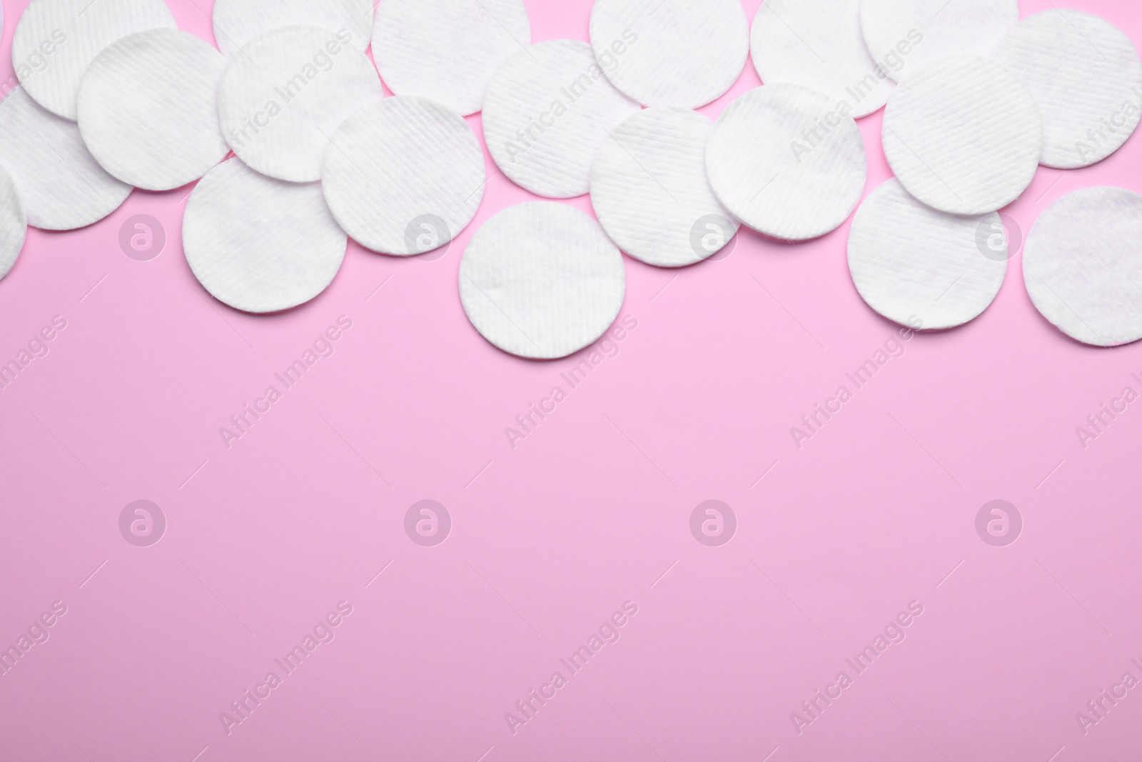 Photo of Soft clean cotton pads on pink background, flat lay. Space for text