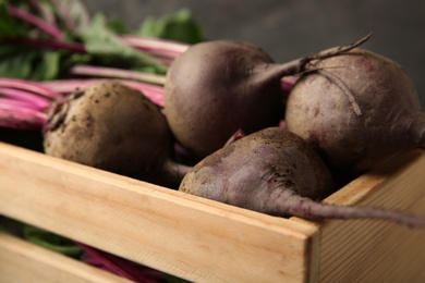 Photo of Wooden crate with fresh organic beets, closeup