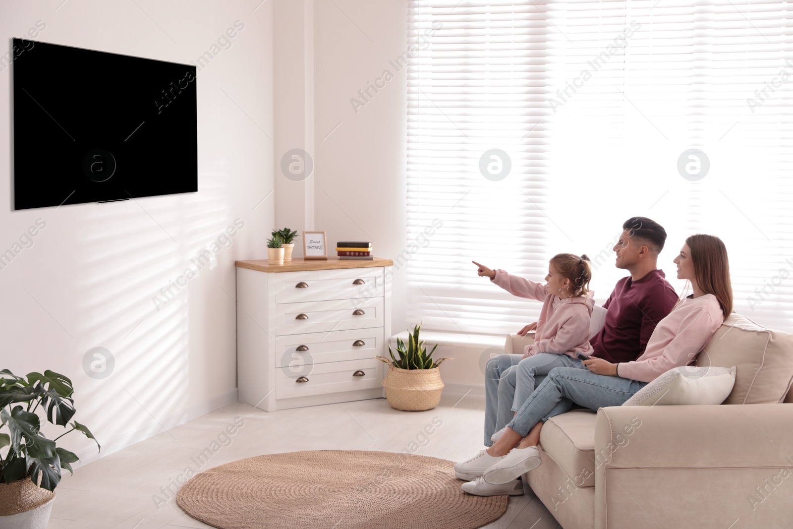 Photo of Happy family watching TV on sofa at home