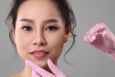 Woman getting facial injection on grey background, closeup