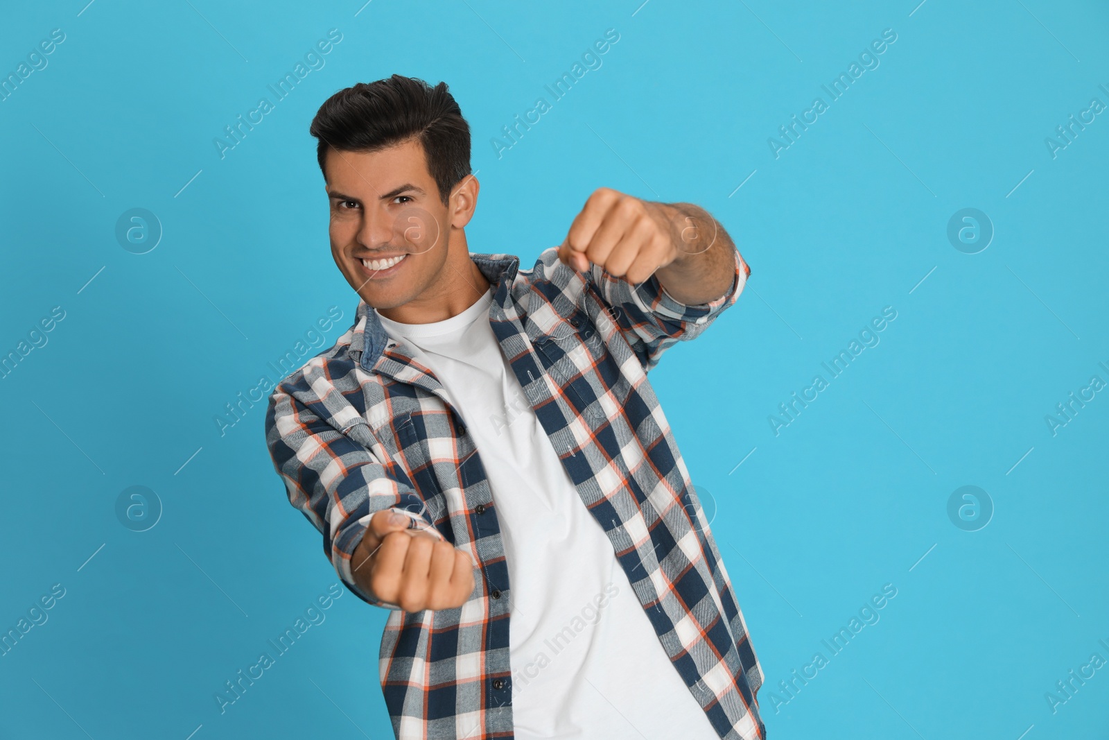 Photo of Happy man pretending to drive car on light blue background