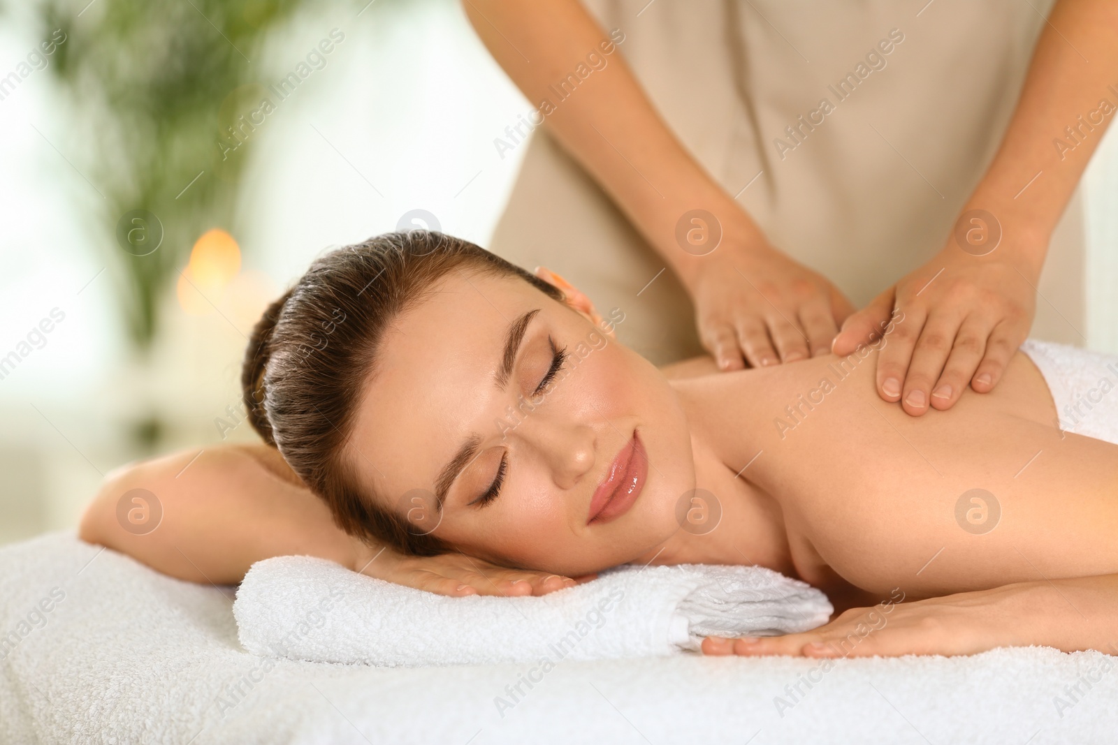 Photo of Beautiful young woman enjoying massage in spa salon