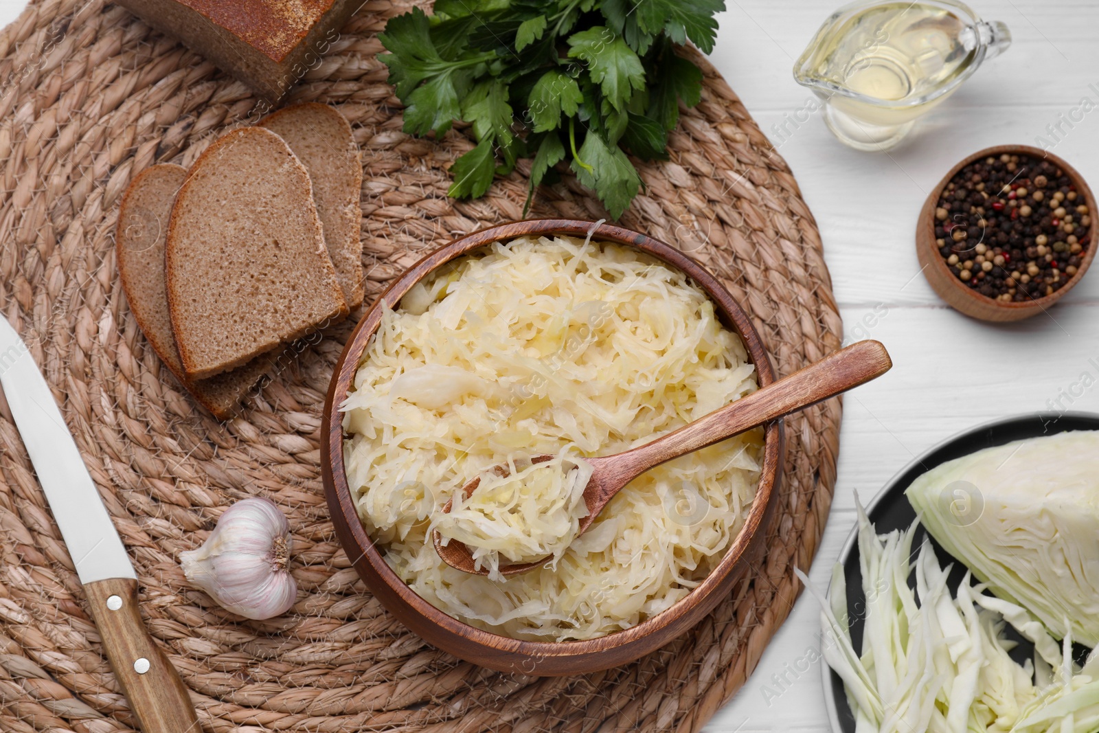 Photo of Bowl of tasty sauerkraut served on white wooden table, flat lay