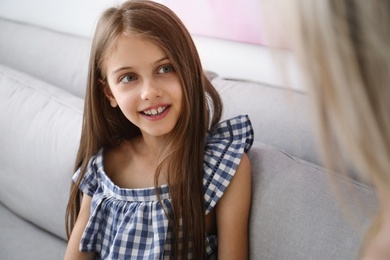 Photo of Cute girl with her mother sitting in sofa at home