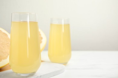 Photo of Glasses of fresh pomelo juice on white table. Space for text