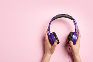 Photo of Woman holding stylish headphones on color background, closeup. Space for text