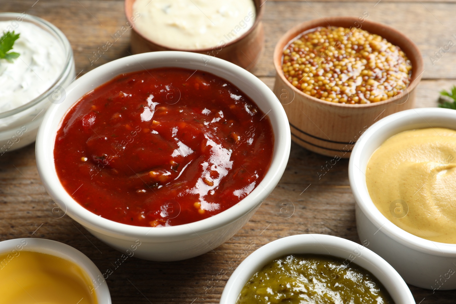 Photo of Set of different delicious sauces on wooden table, closeup