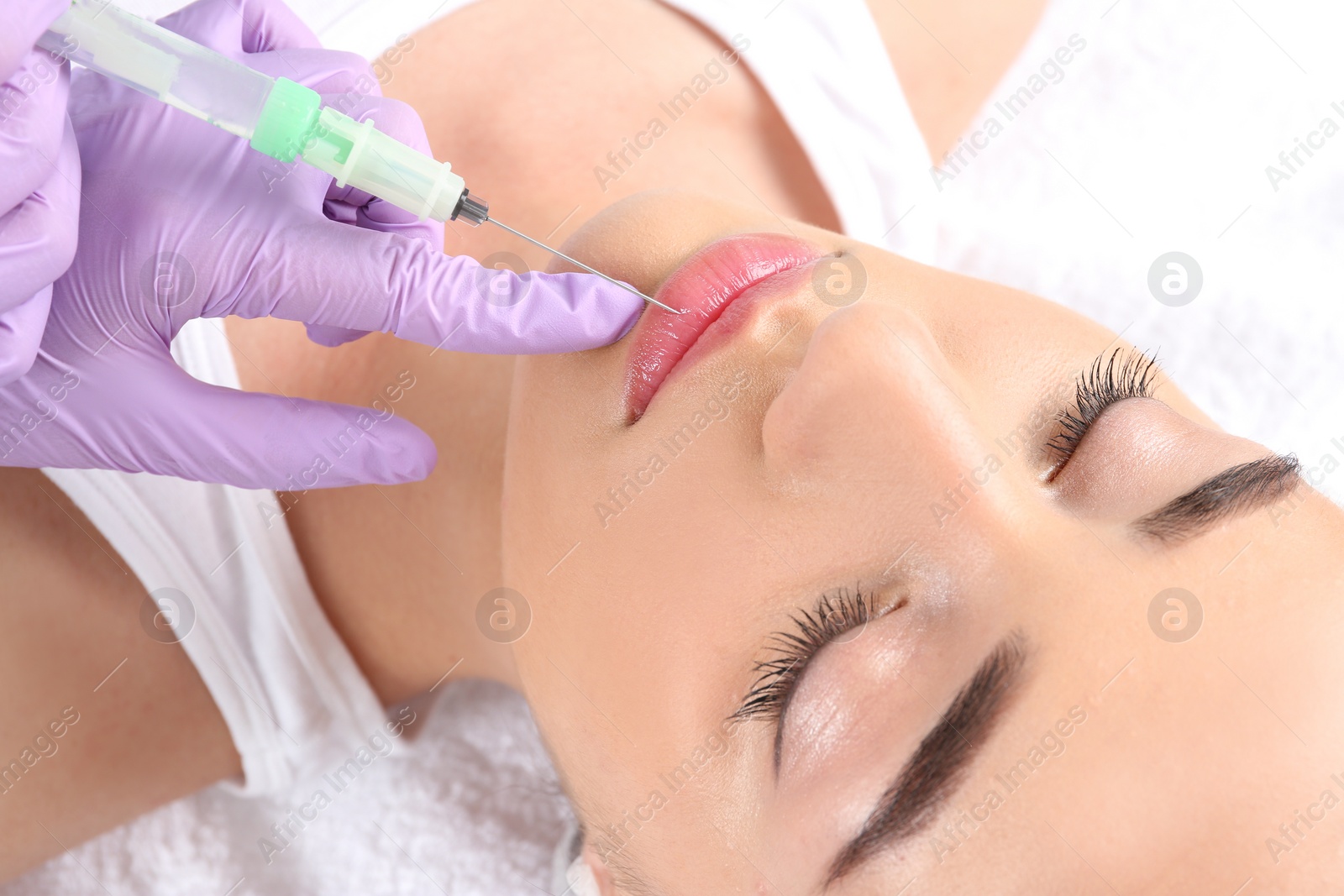 Photo of Young woman getting lip injection in beautician salon, closeup