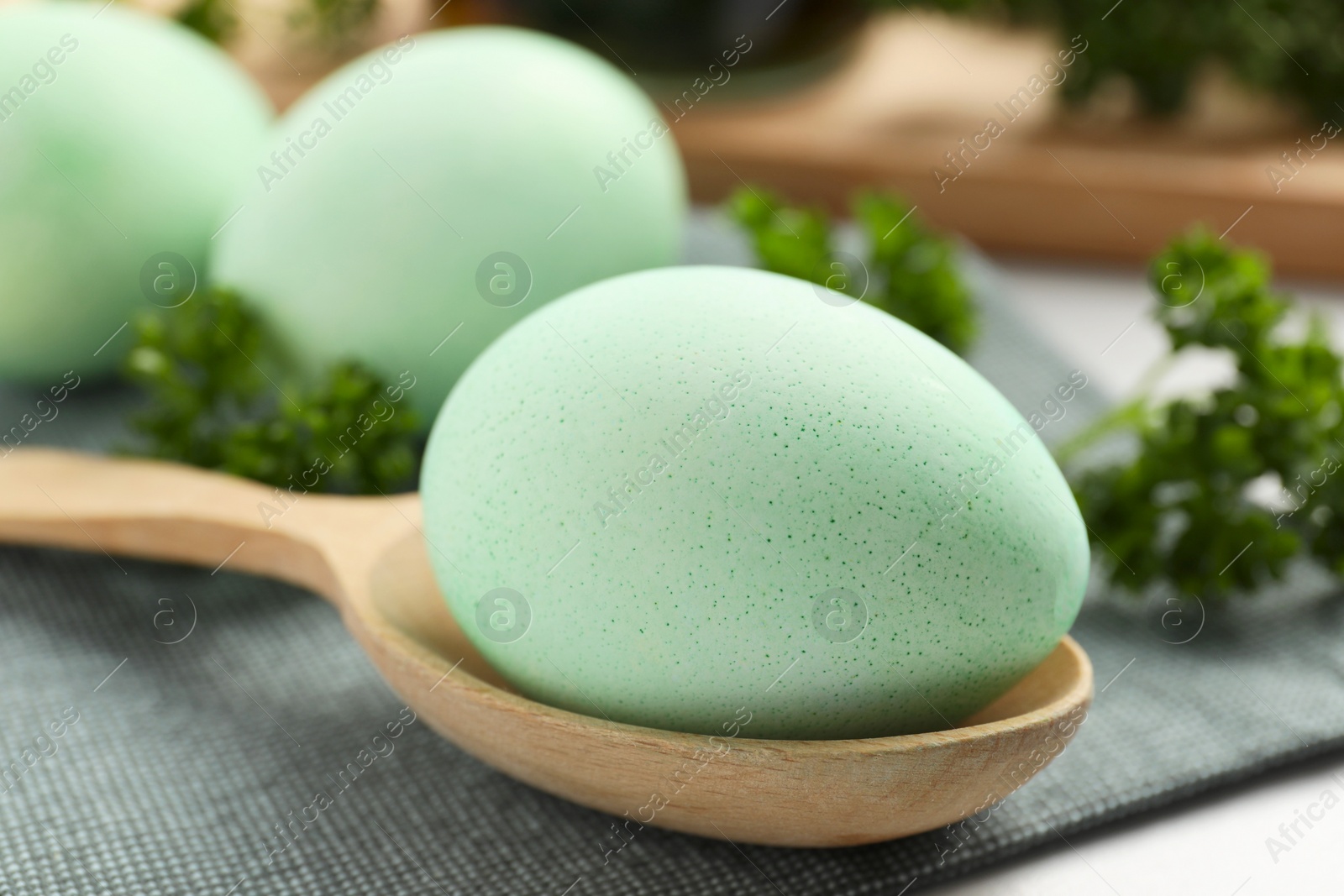 Photo of Turquoise Easter eggs painted with natural dye and curly parsley on table, closeup