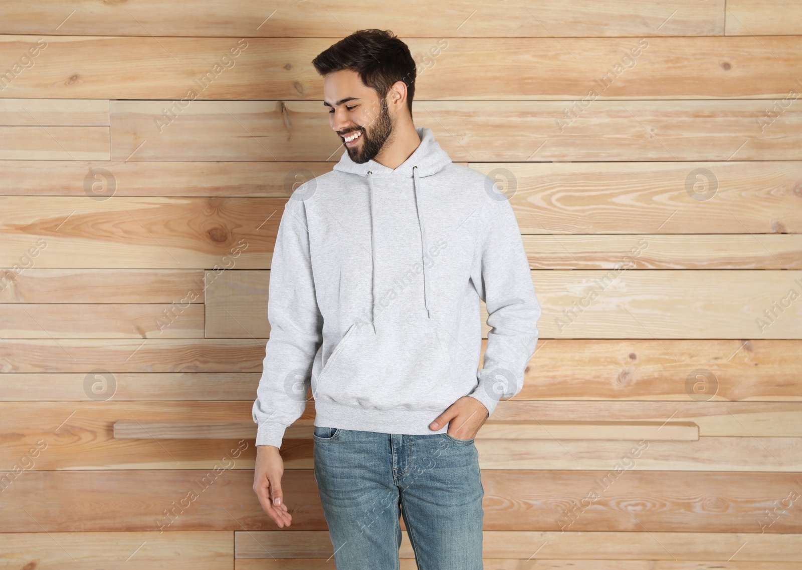 Photo of Portrait of young man in sweater at wooden wall. Mock up for design