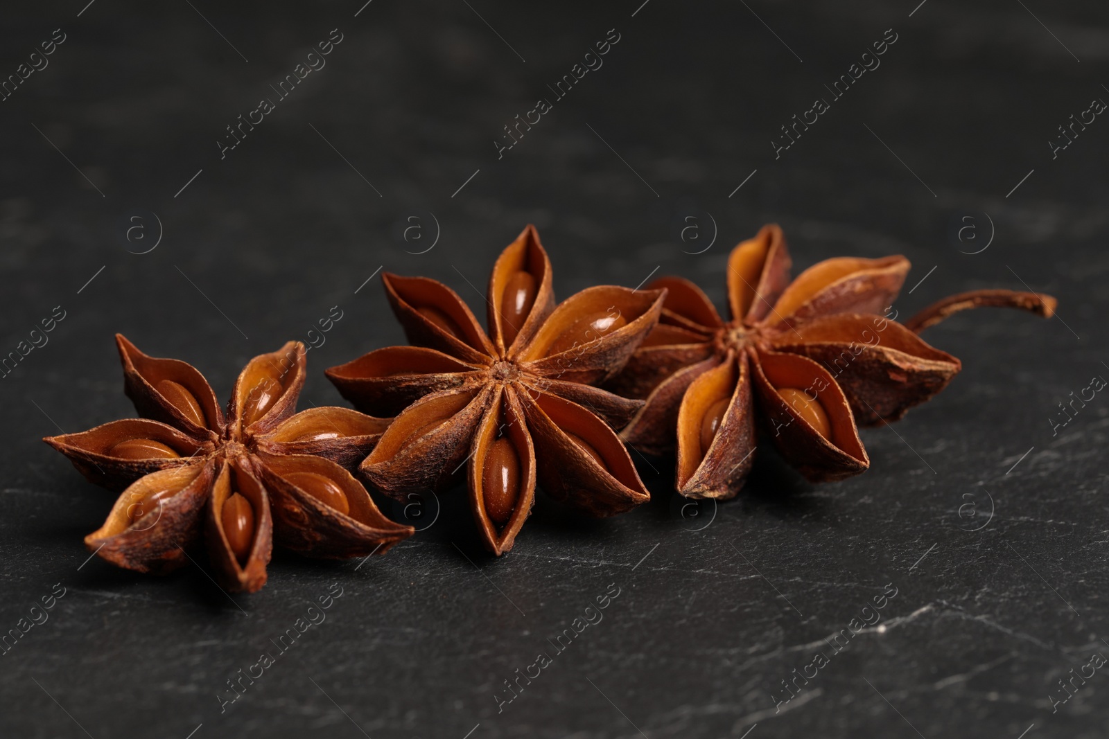 Photo of Aromatic anise stars on black table, closeup