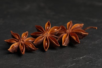 Photo of Aromatic anise stars on black table, closeup