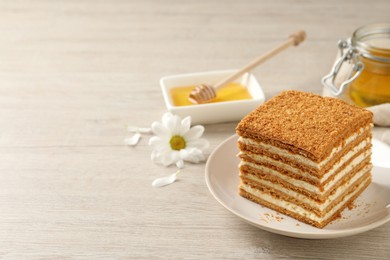 Photo of Slice of delicious layered honey cake served on wooden table. Space for text