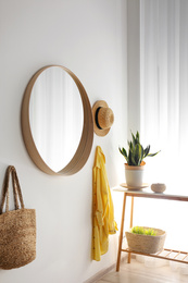 Photo of Round mirror with wooden frame on white wall in light room