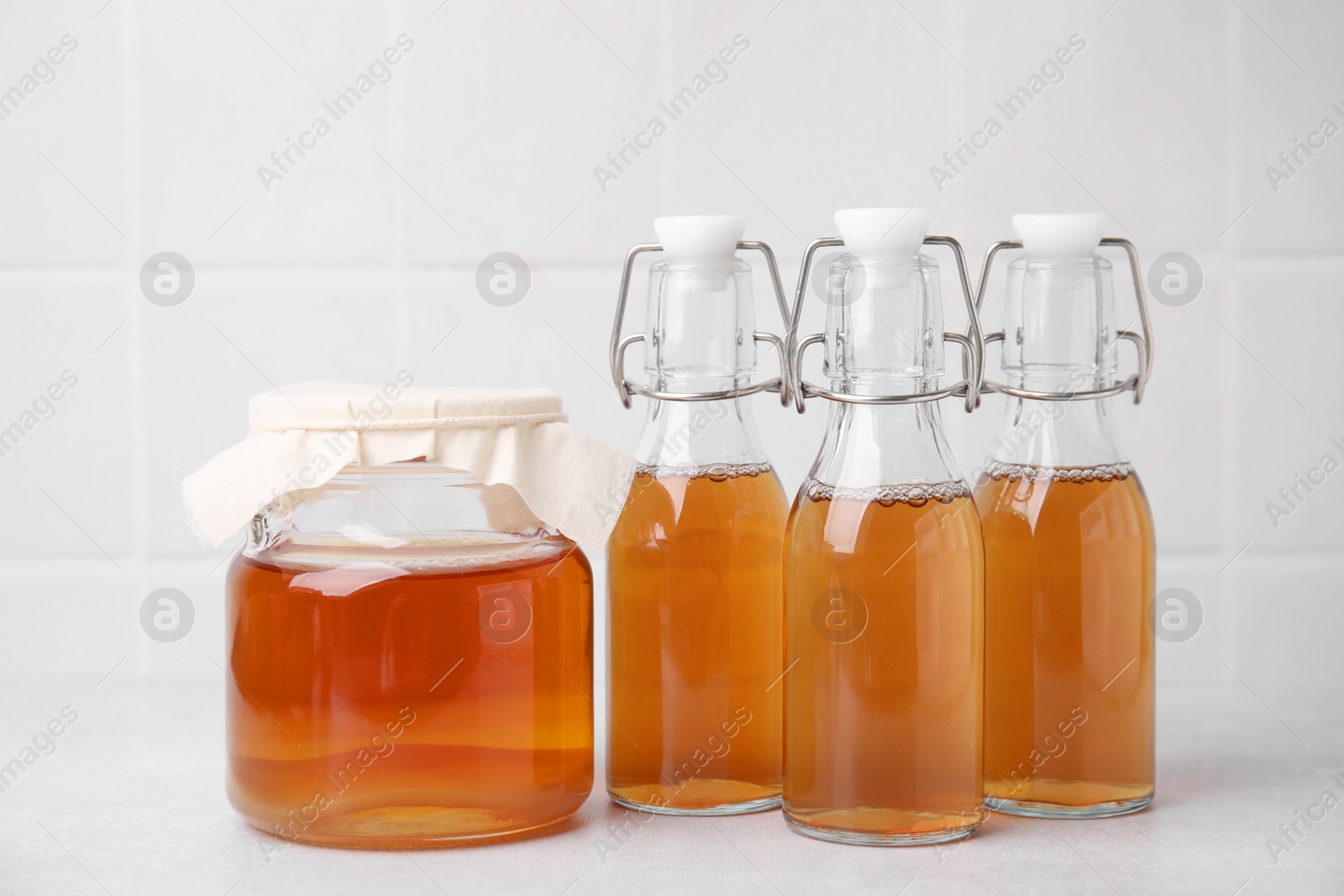 Photo of Tasty kombucha in glass jar and bottles on white table