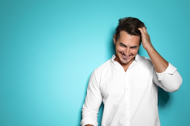 Young man with trendy hairstyle posing on color background