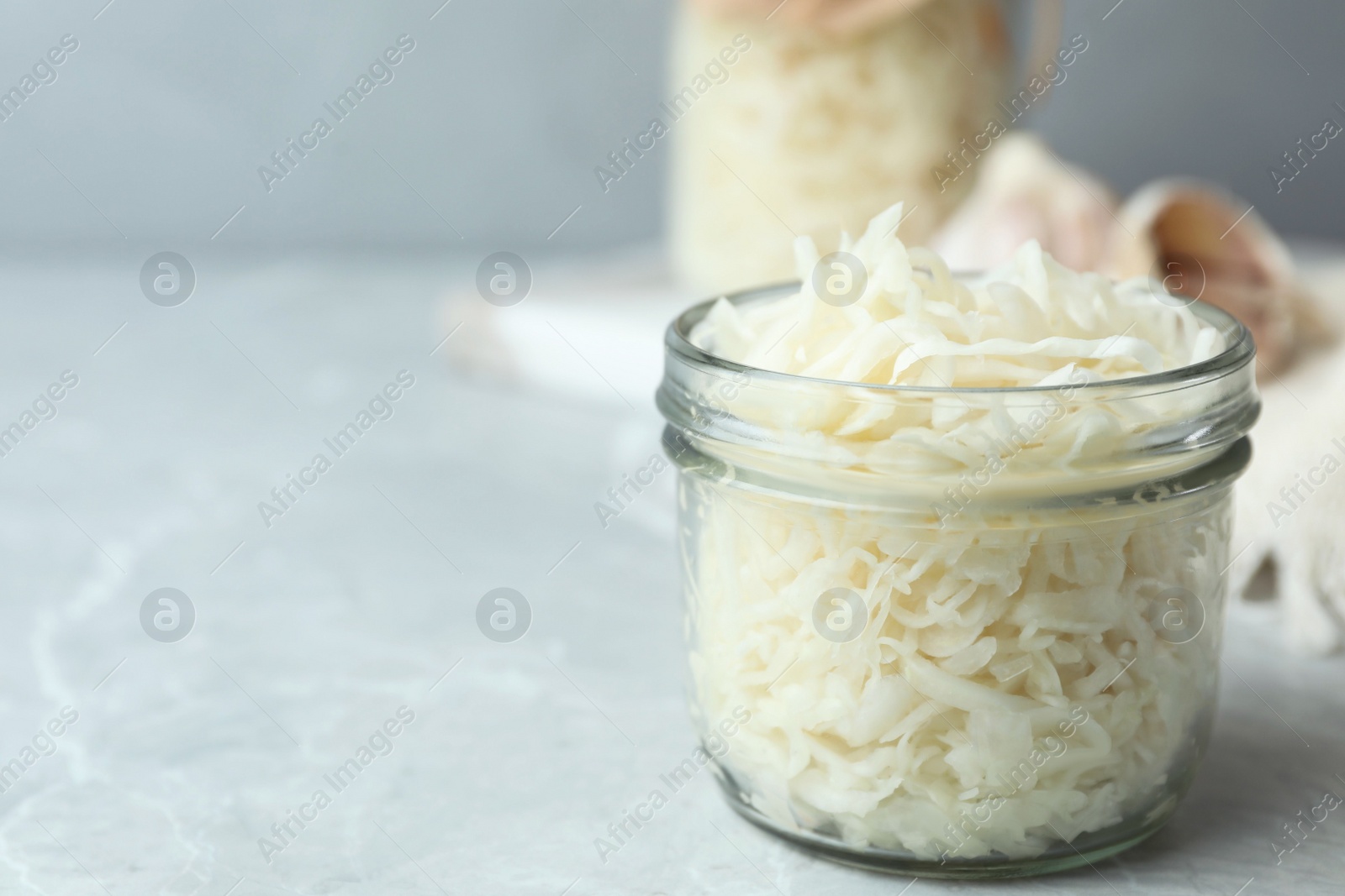 Photo of Tasty fermented cabbage on light grey marble table, closeup